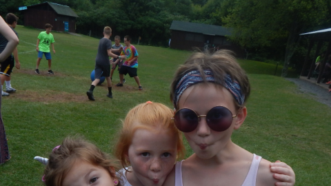 Three campers standing together making fish faces with pursed lips into the camera.