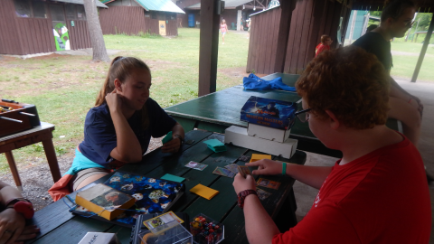 Youth playing Magic card game with counselor.