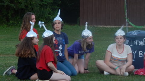 Campers seated together wearing tin foil hats.
