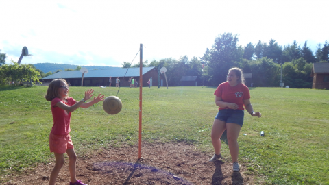 camper playing tether ball with counselor.