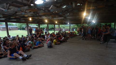 campers seated in the rec pavilion as a group of campers perform a skit.